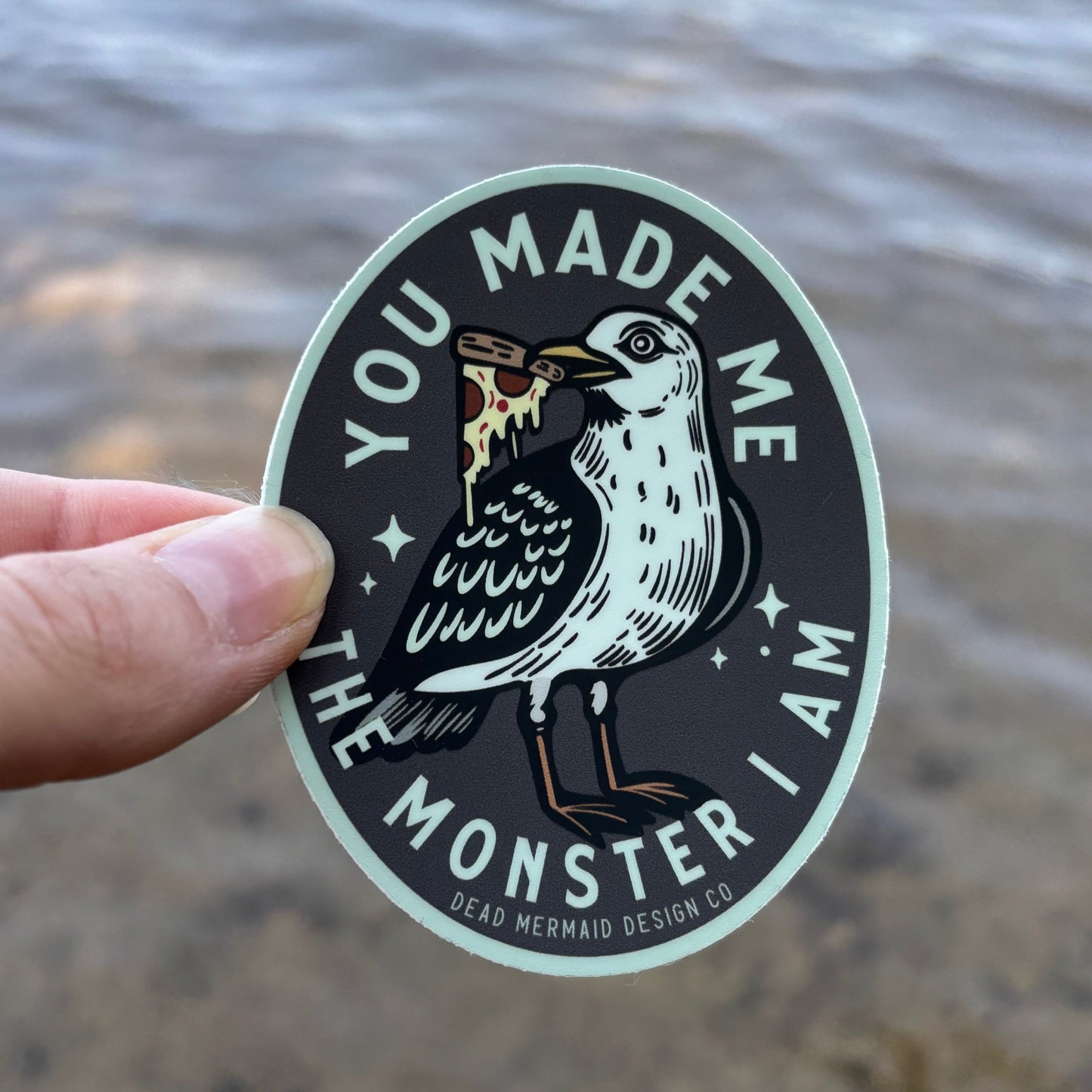 Sticker with a design of a bird and text held by a hand against a textured background