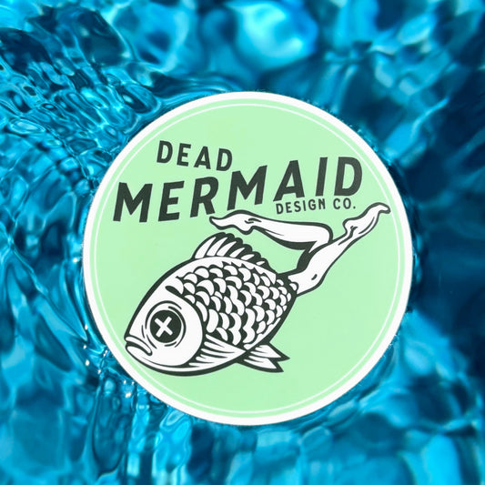 Dead Mermaid Design Co. logo on a light green circle with water background