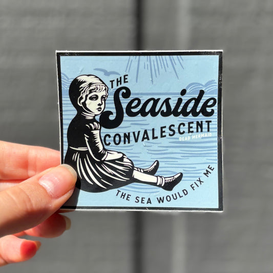 Hand holding a square sticker with 'The Seaside Convalescent' design against a gray background